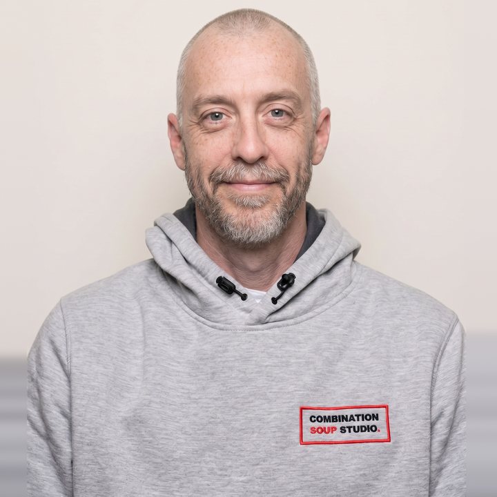 Portrait of Chris Murdock in the studio's grey hoodie, smiling.